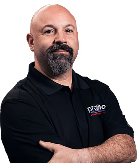 Bald man with a goatee wearing a black polo shirt with crossed arms.