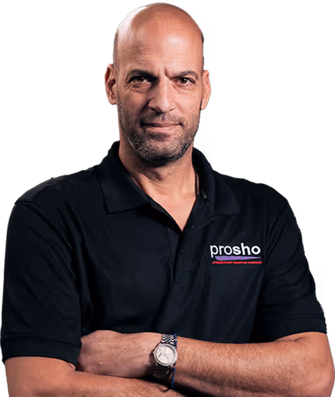 Confident bald man in a black polo shirt with crossed arms and a watch on his wrist.