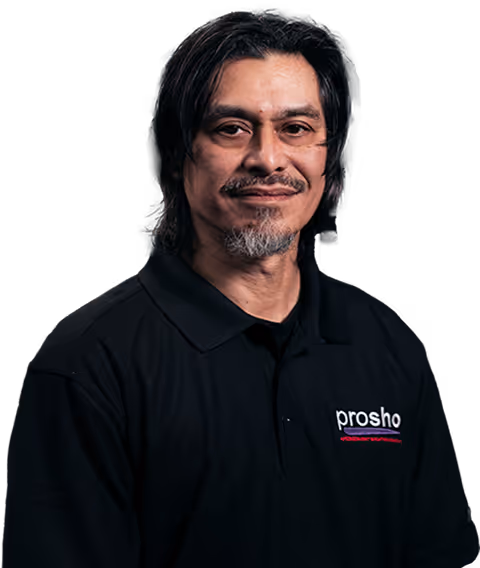 Man with dark hair and a goatee wearing a black polo shirt with the prosho logo on it, against a black background.