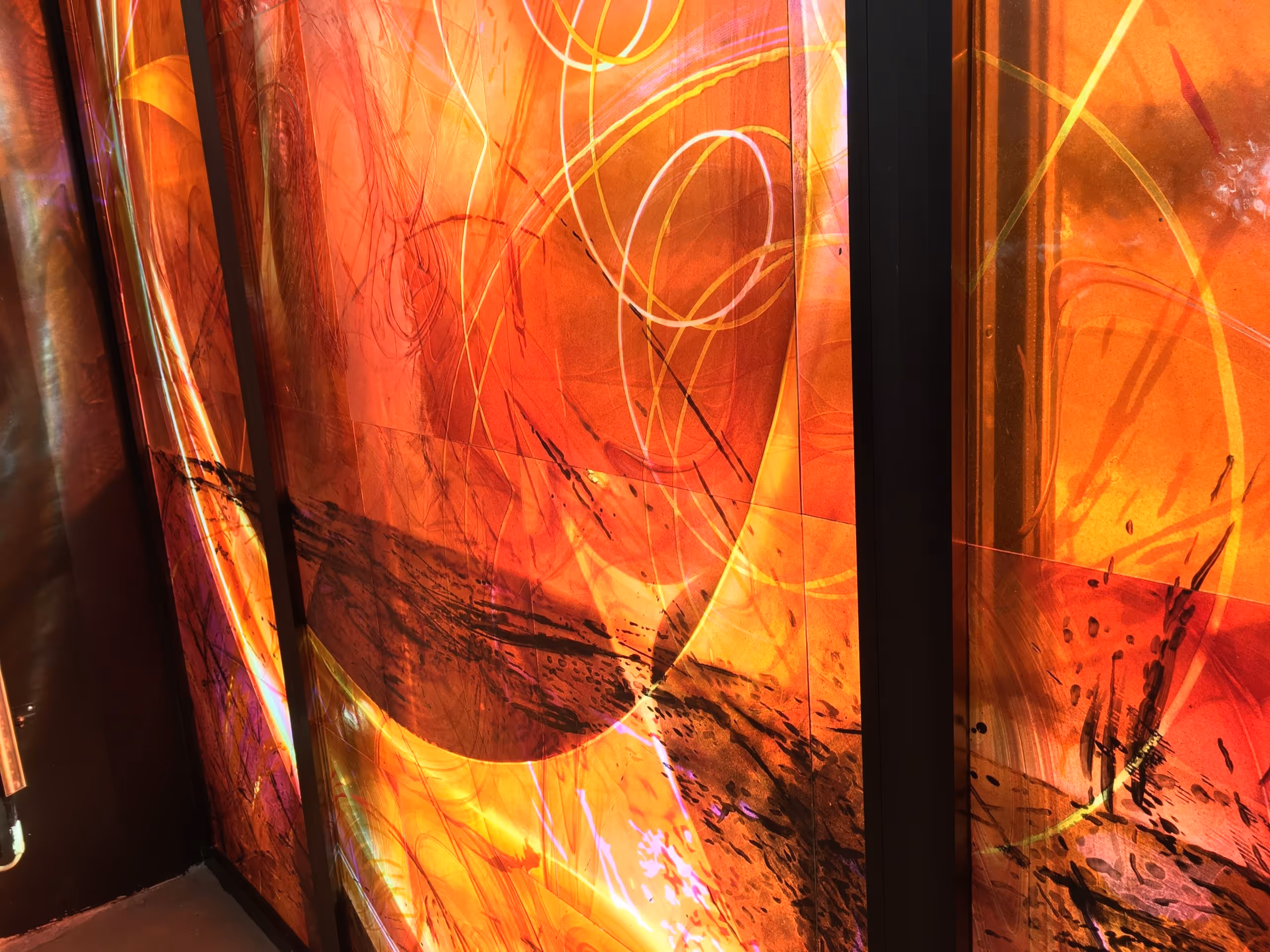 Abstract wall panels with vibrant orange, red, and yellow swirling patterns and black vertical dividers.