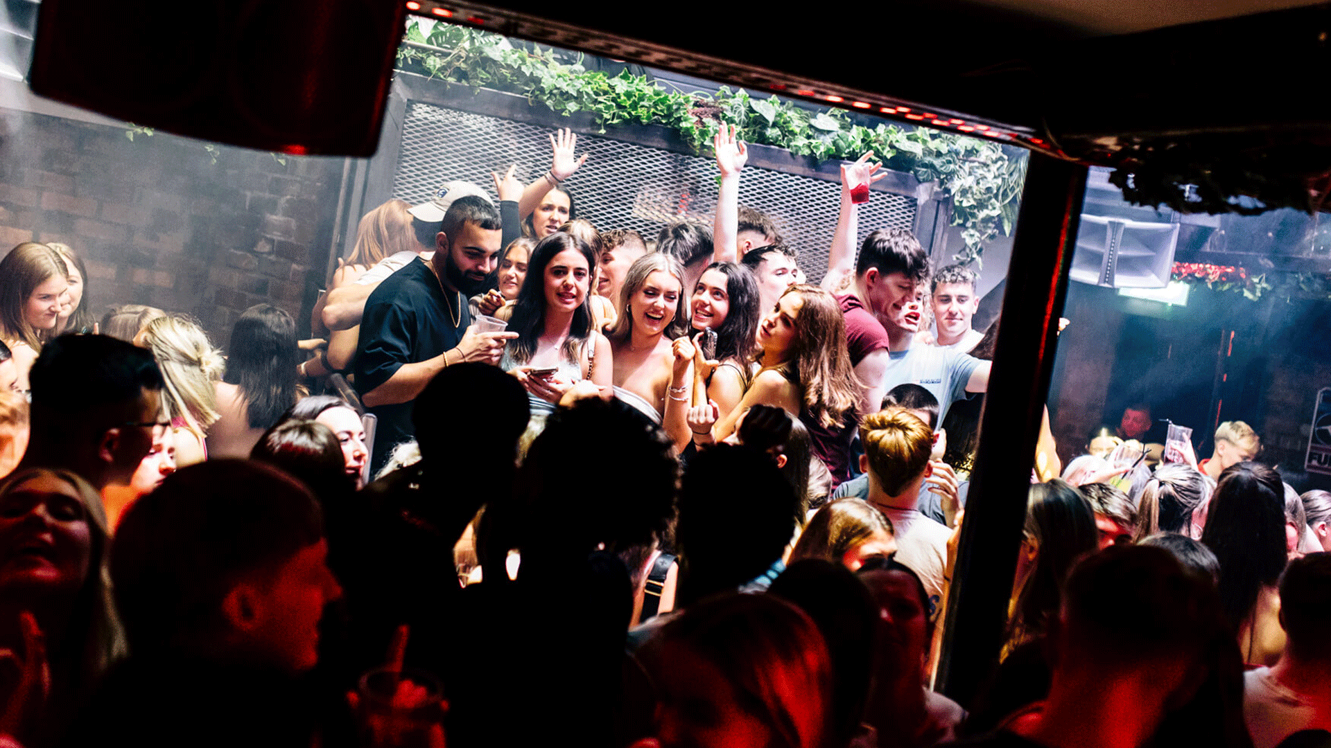 A vibrant club scene at Thompsons Garage, with crowds dancing and enjoying the atmosphere during a club night. People are socializing, some are holding drinks, embodying the Belfast nightlife experience with house music playing in the background.