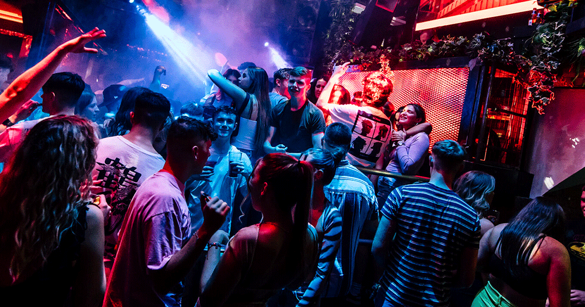 A lively scene at a Belfast Nightclub with people dancing and enjoying a Club Night. Vibrant lights create an energetic atmosphere. Guests are gathered near the DJ booth, highlighting the House Music vibe at Thompsons Garage, a popular location for Belfast Nightlife.