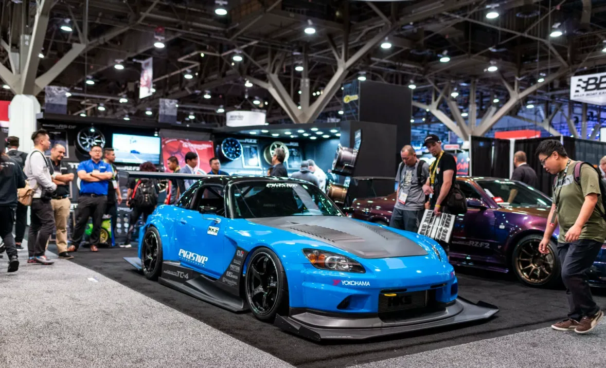A blue modified sports car on display among visitors at the SEMA Show