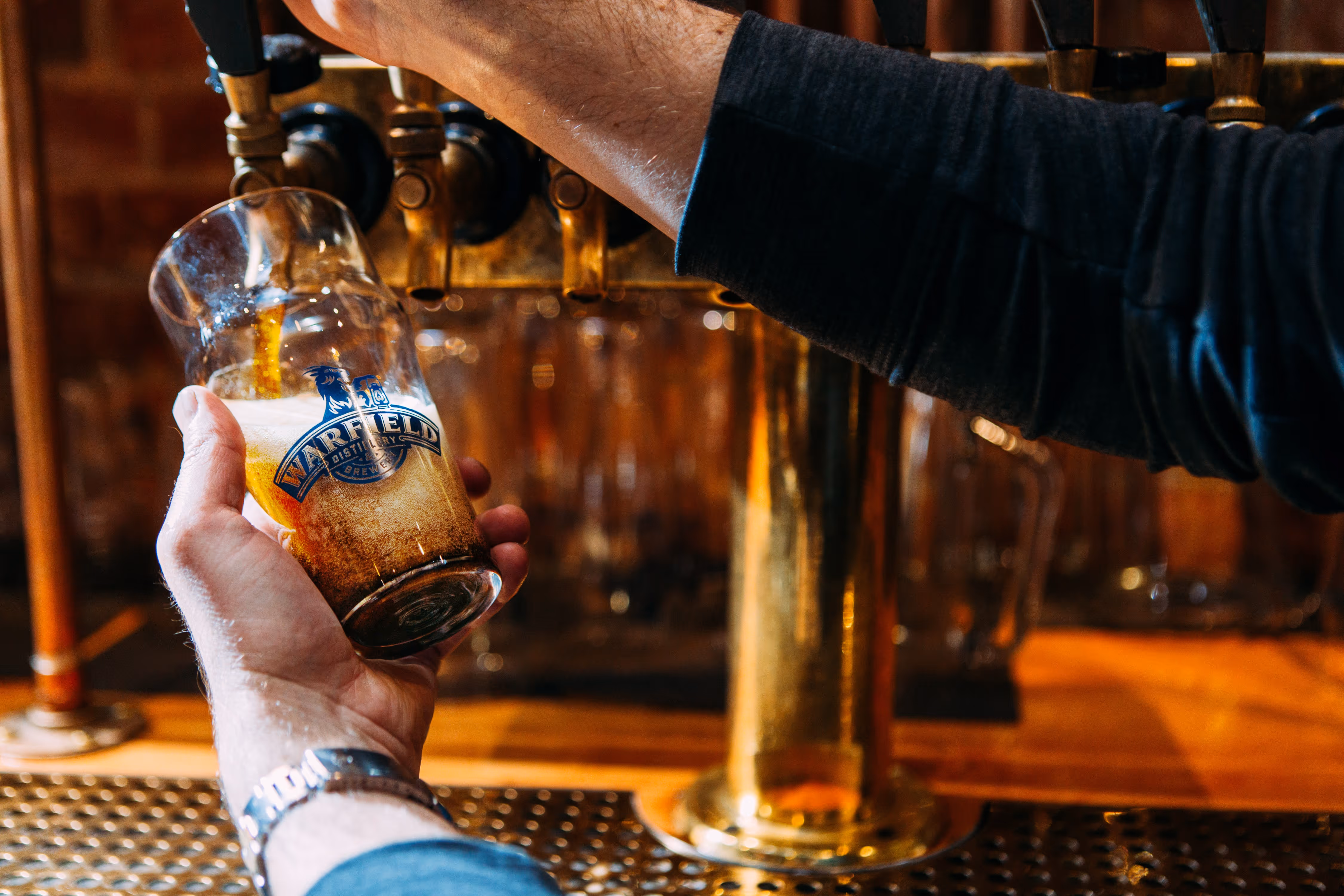 Hands filling beer glass from tap