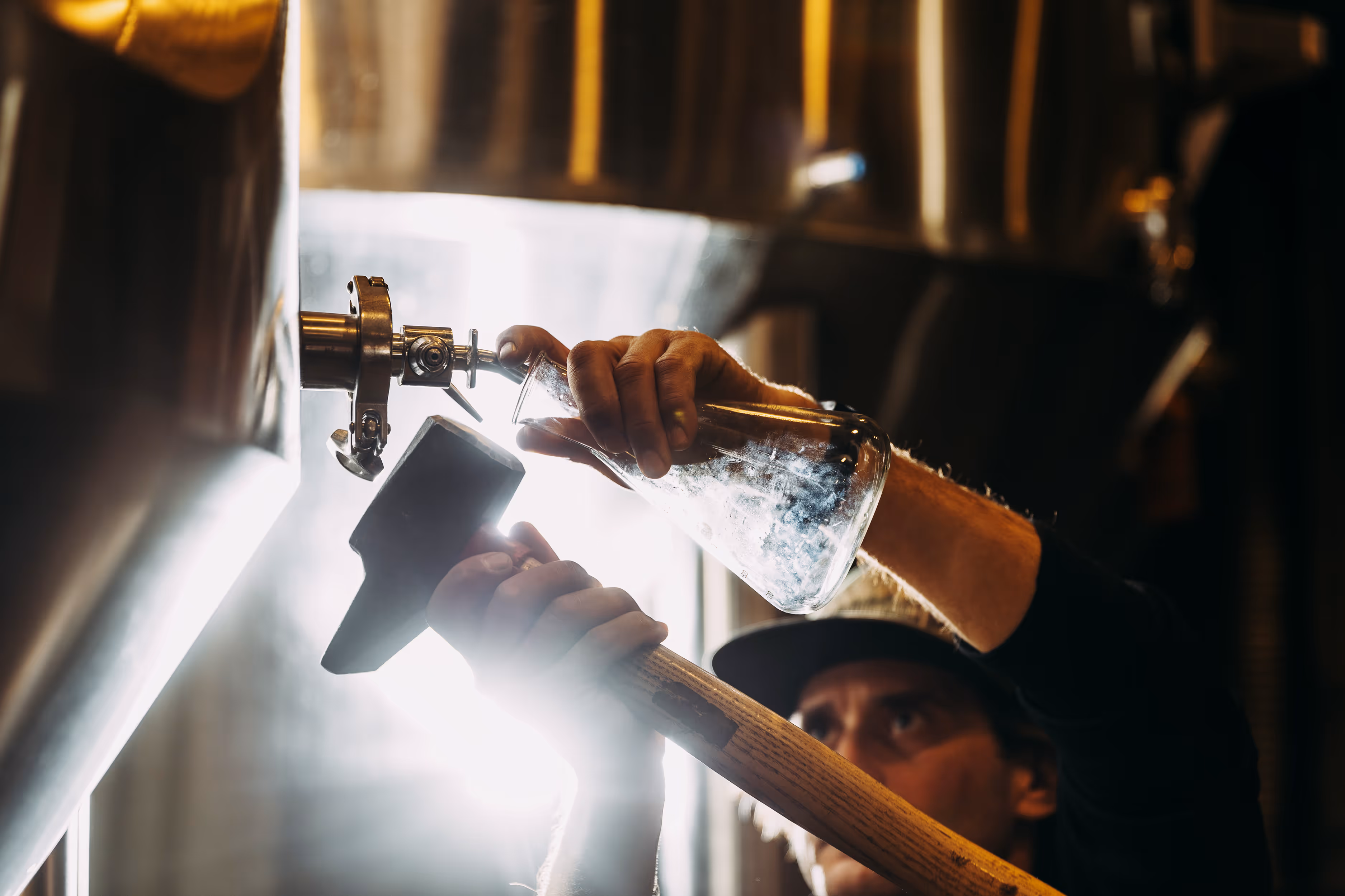 man tapping distiller with hammer