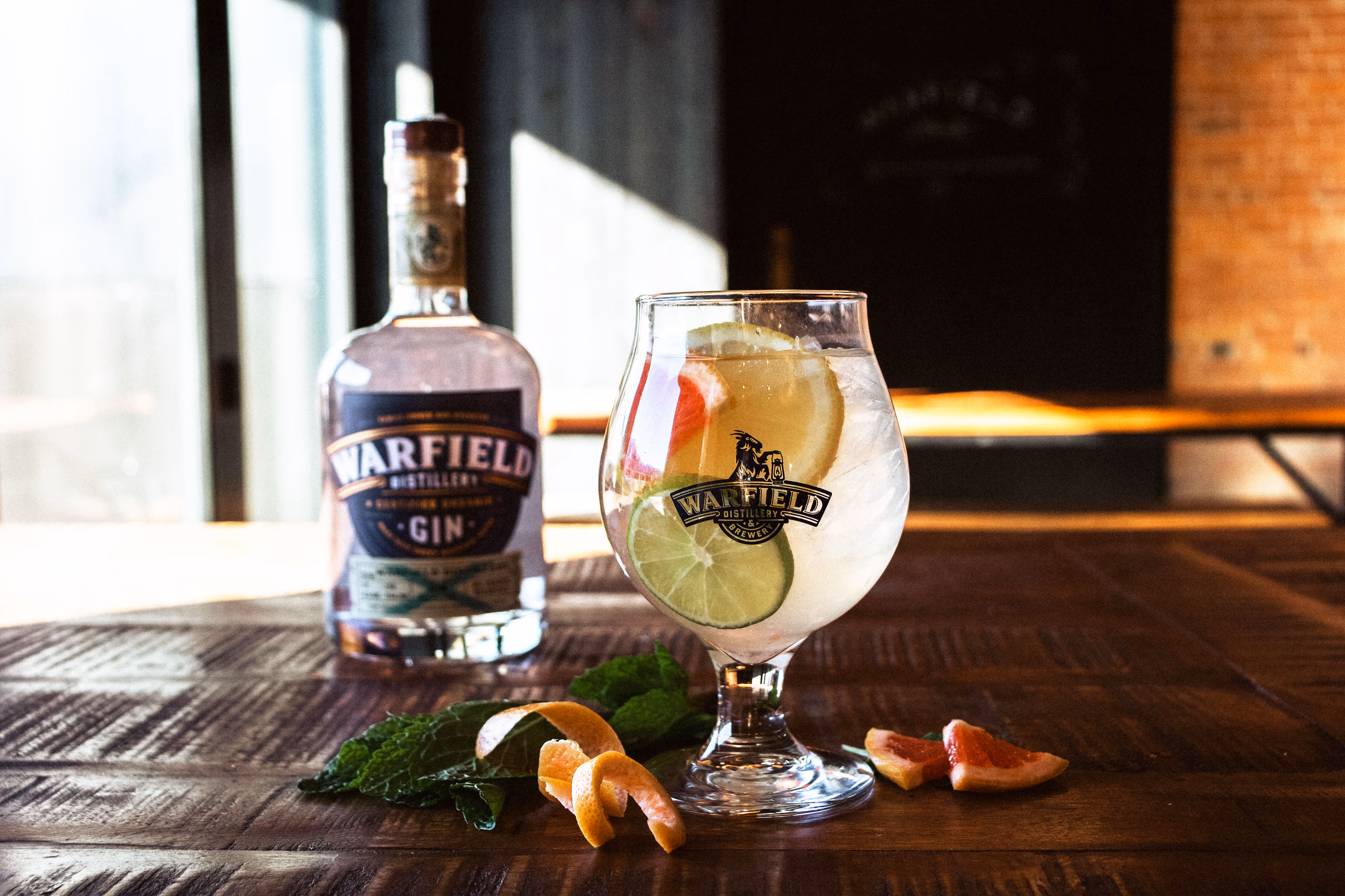 Gin bottle behind cocktail drink with fruit on a table