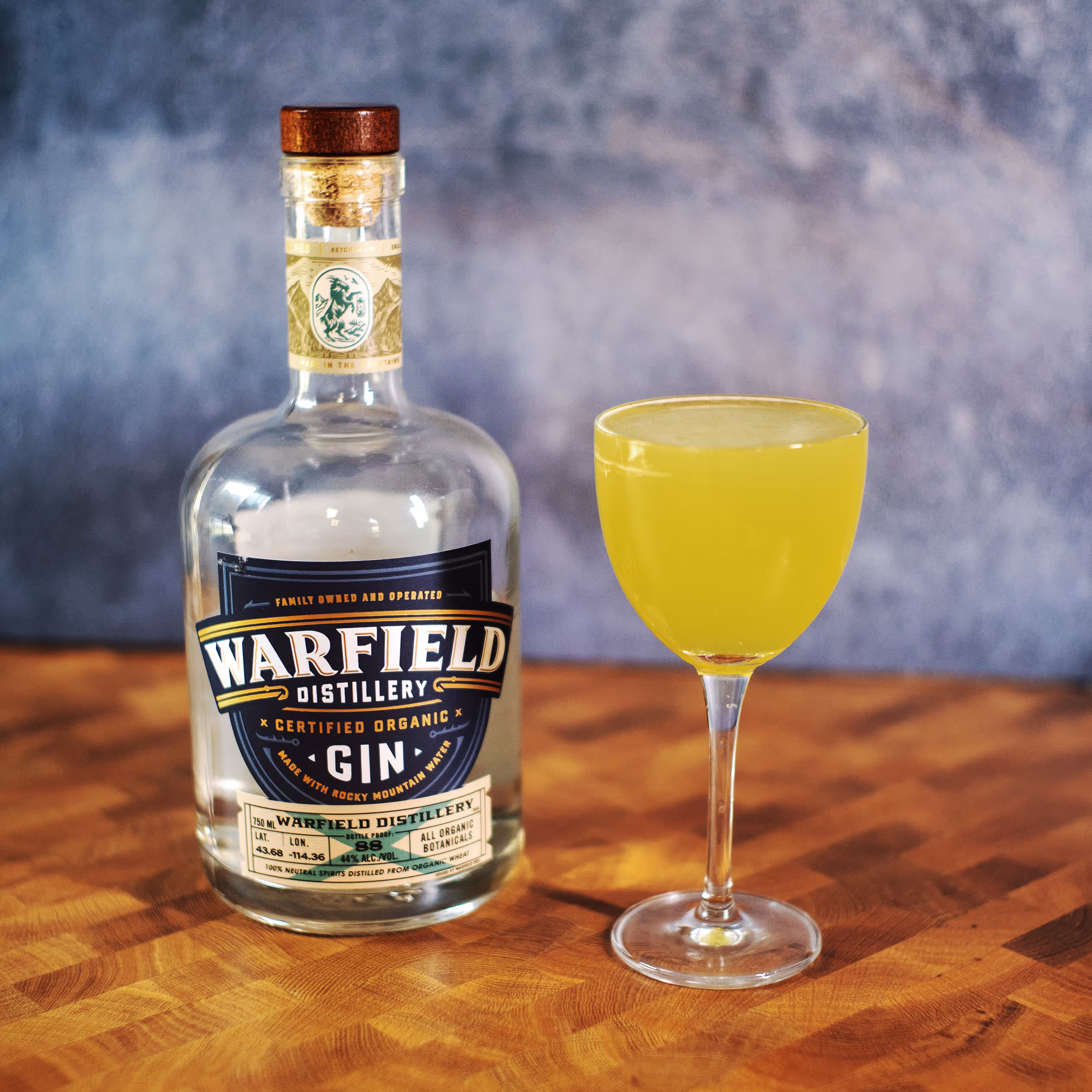 Gin bottle next to yellow cocktail