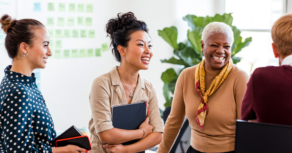 4 women in an office happily engaging in a conversation