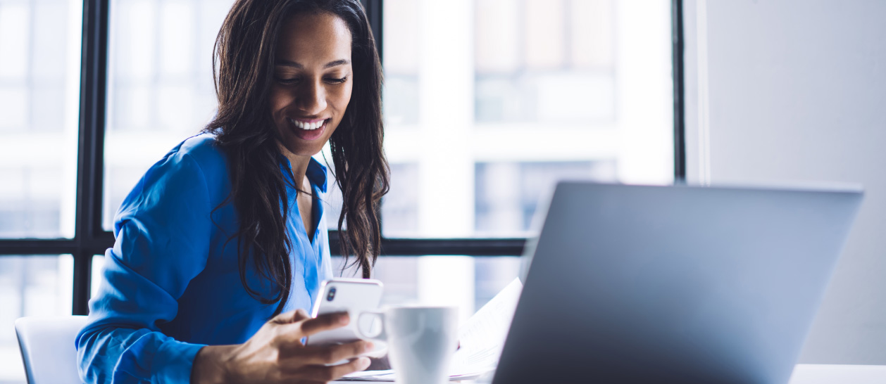 An employee on her desk checking documentation and confirming with the phone
