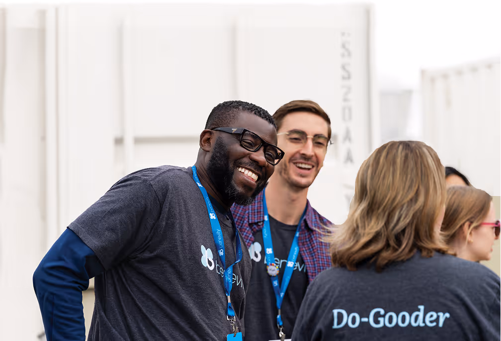 Smiling diverse group of people wearing Benevity shirts and lanyards at an outdoor event.