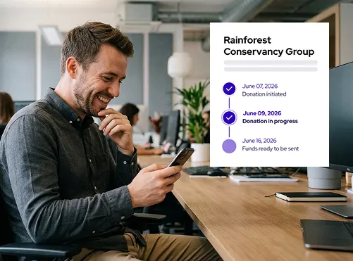 Man sitting at a desk and smiling while looking at his phone with a Rainforest Conservancy Group donation progress timeline showing three dates and statuses.
