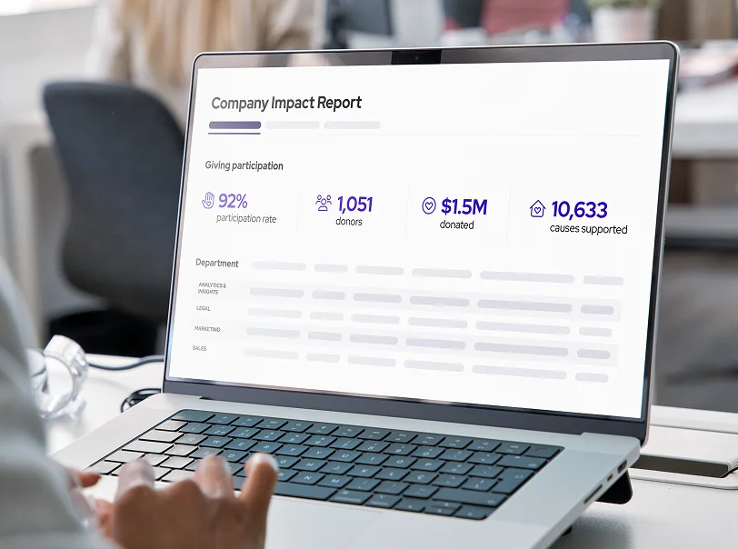 Laptop screen showing a Company Impact Report with 92% participation rate, 1,051 donors, $1.5M donated, and 10,633 causes supported.