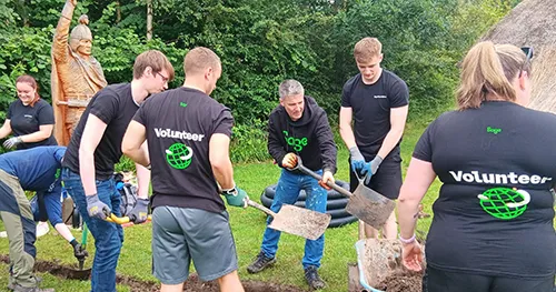 Sage employees volunteering outdoors by digging and landscaping together.
