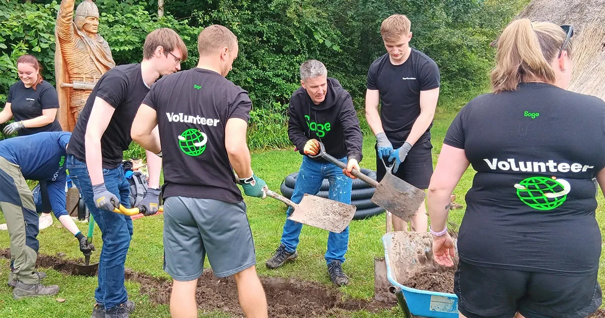 Sage employees volunteering outdoors by digging and landscaping together.
