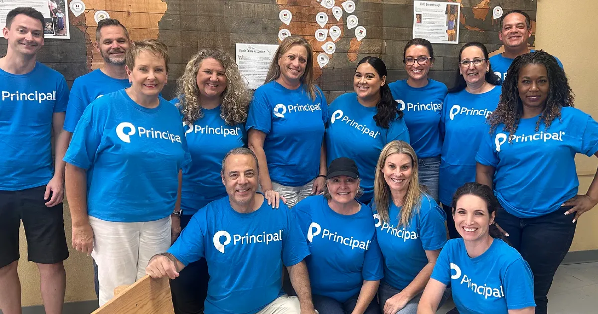 Principal employees in matching shirts posing during a team volunteer event.