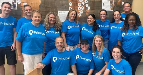 Principal employees in matching shirts posing during a team volunteer event.