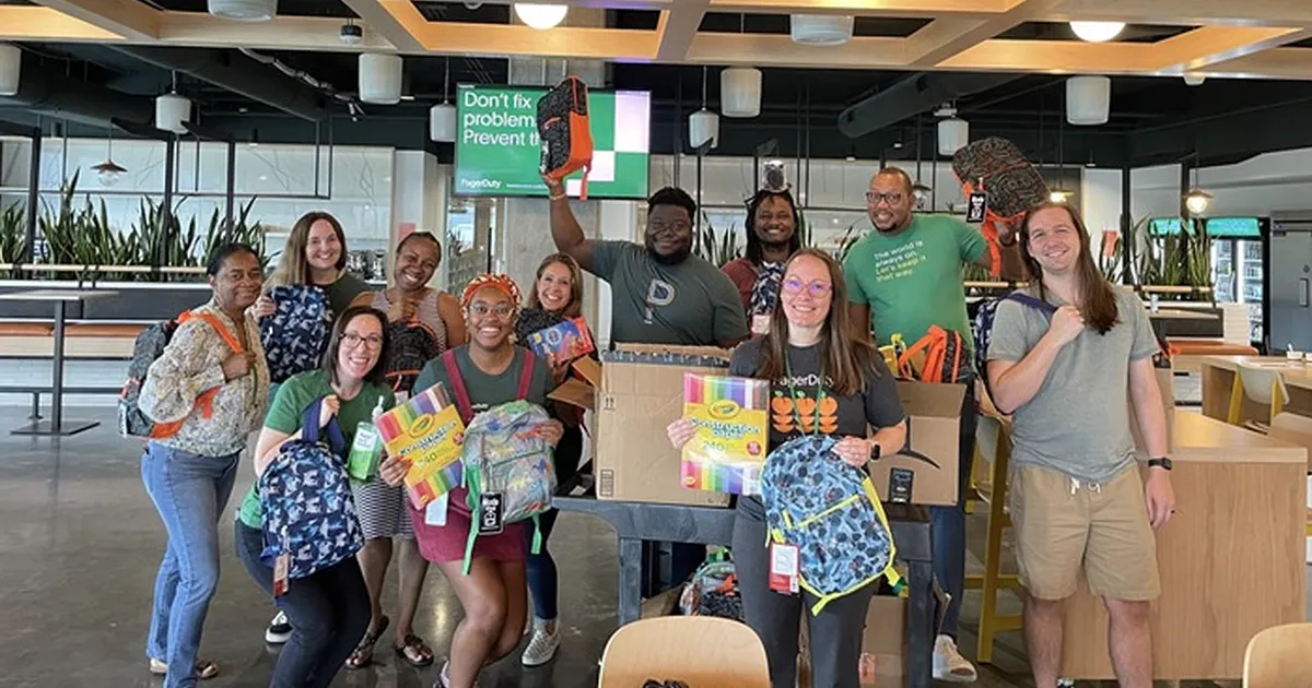 PagerDuty employees holding school supplies during a volunteer backpack drive.