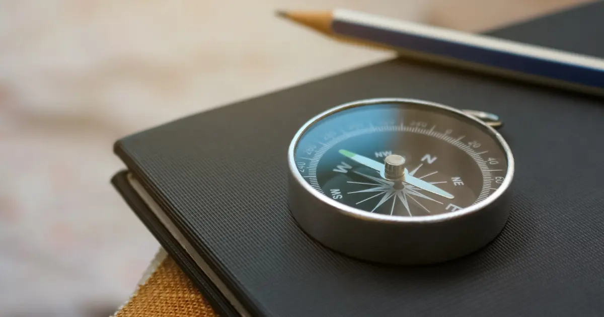 A close-up of a compass resting on a closed black notebook, representing guidance and direction for CSR programs.