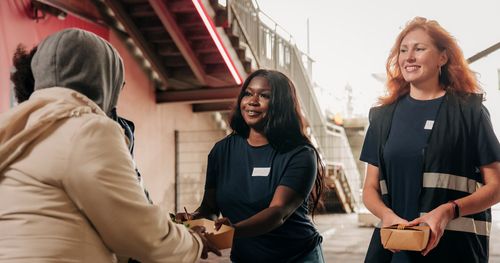 Two women giving food in a giving volunteering