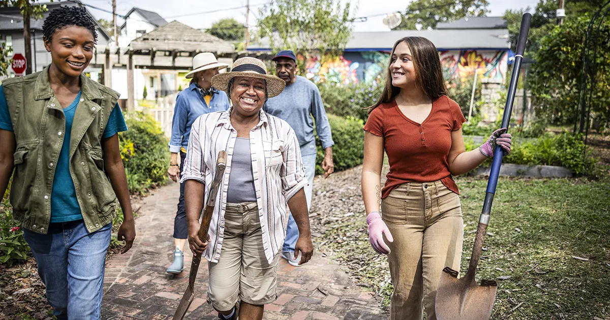 Group of individuals carrying shovels for a community garden.