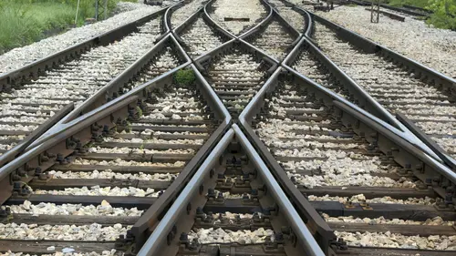A close-up view of intersecting railway tracks with gravel between the rails, showing multiple switches for changing train direction.