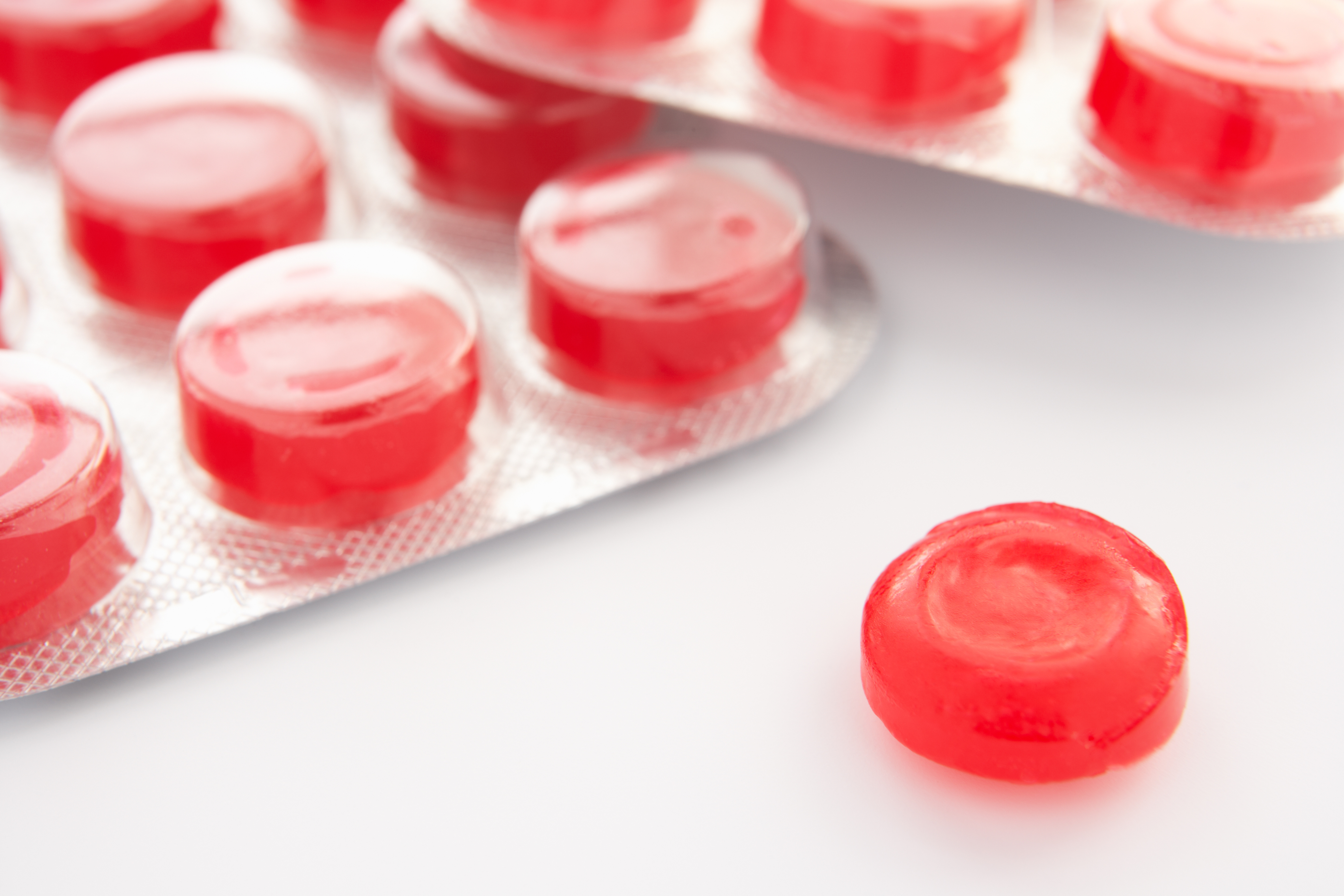 Close-up of red throat lozenges in a blister pack used for sore throat relief