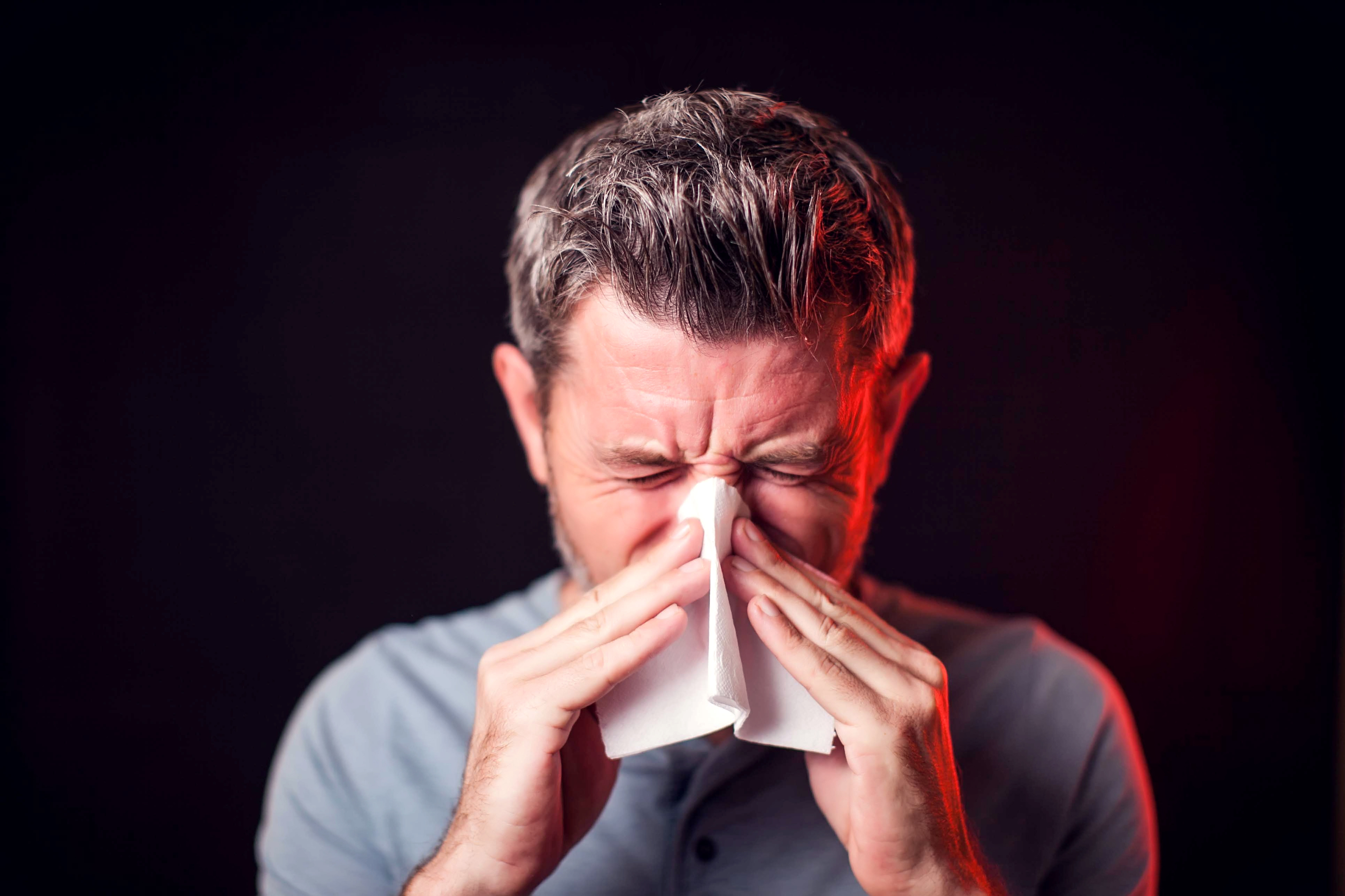 Man pressing nose due to sinus pressure and nasal congestion from swollen nasal passages