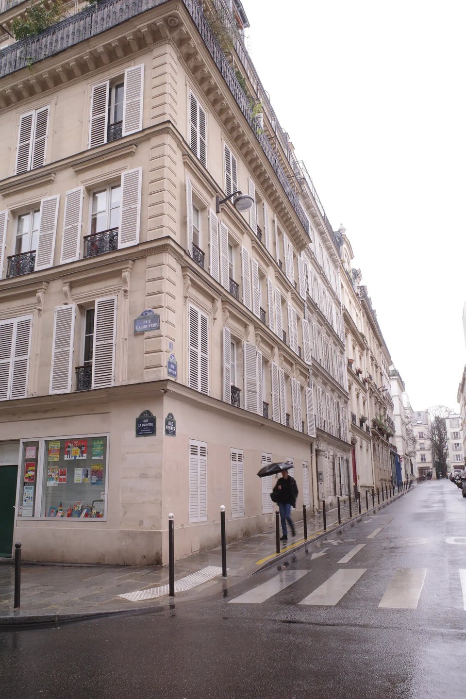 A rainy day in Paris, a man in a black jacket and with a black umbrella walks down an empty street