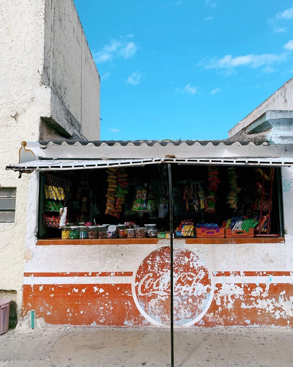 a kiosk in Cancun, with a worn-out Cola Cola sign painted in front of it