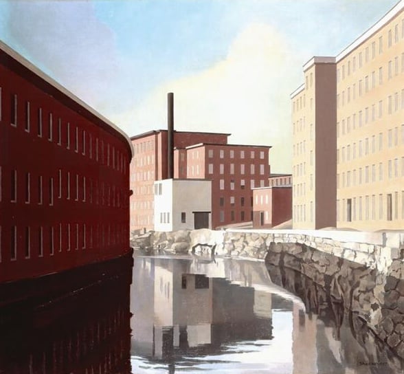 Geometric mill buildings in red and beige reflect in a still canal under a pale blue sky, creating a quiet, balanced industrial landscape.