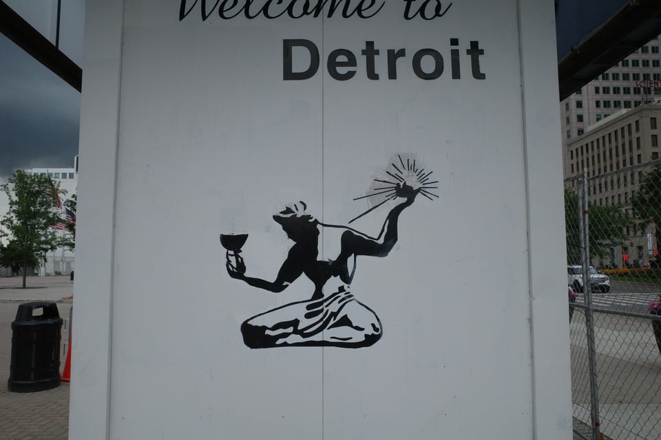 Black painted silhouette of the Spirit of Detroit with “Welcome to Detroit” above it.