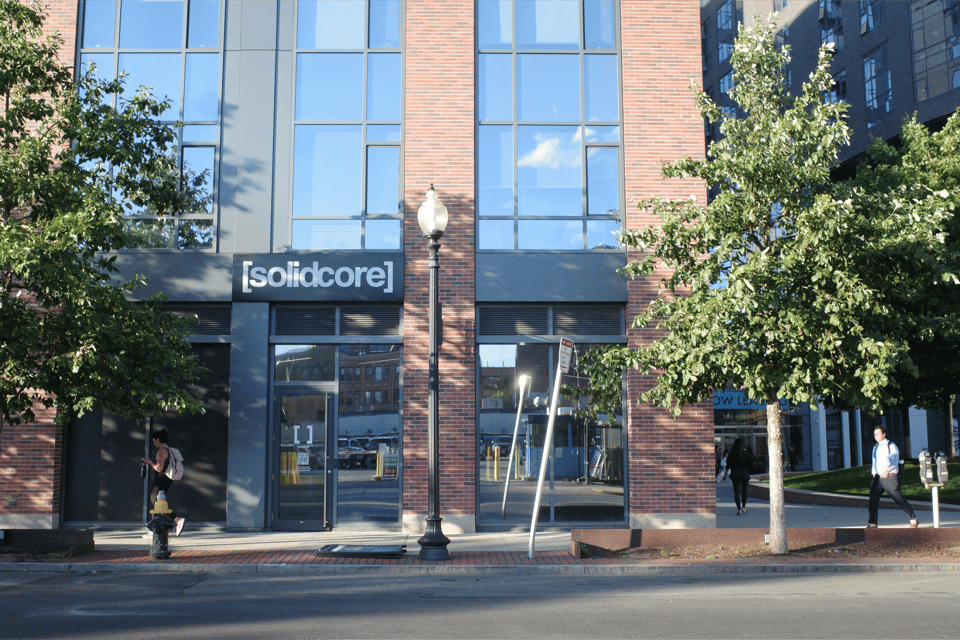 Street-level view of a brick and glass building with a “solidcore” fitness studio sign; the ground-floor windows are blacked out, creating a dark, opaque facade.