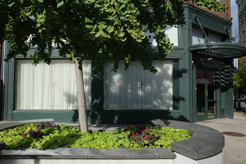 A corner restaurant inside a green-painted historic building, with its large windows fully curtained off.