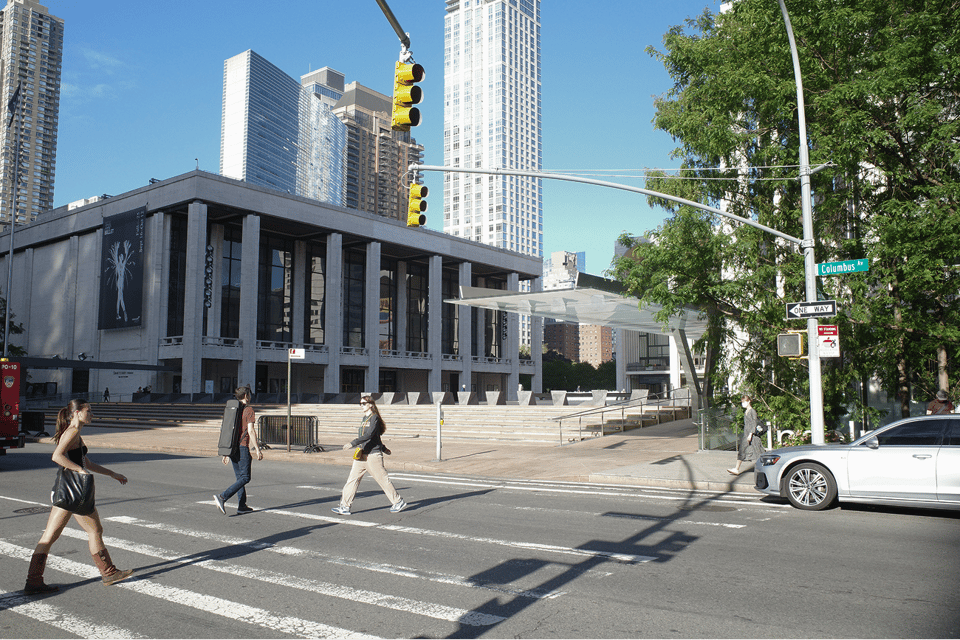 People crossing the street toward Lincoln Center on a sunny day.