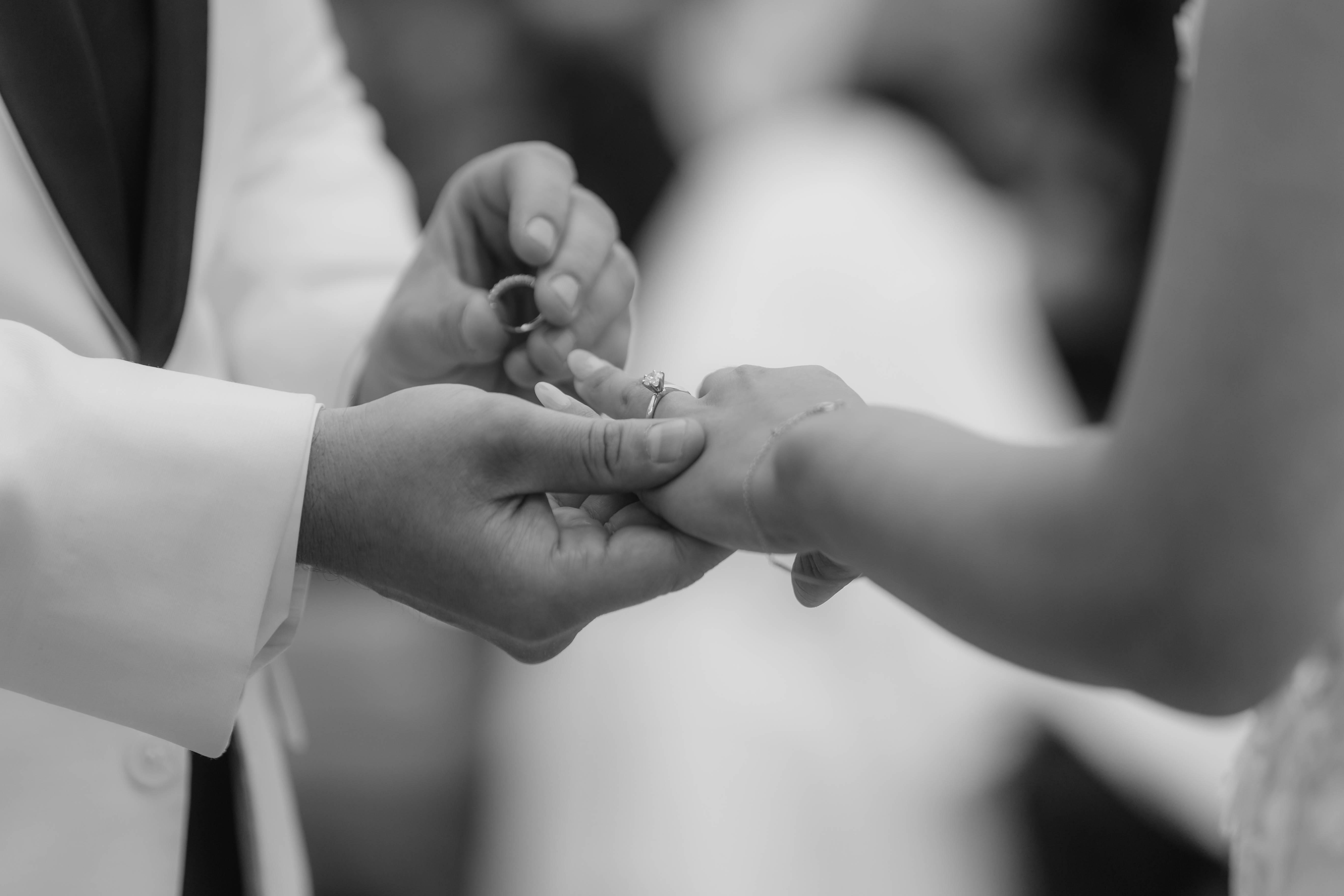 Close-up of a groom placing a wedding ring on a bride's finger during a ceremony.