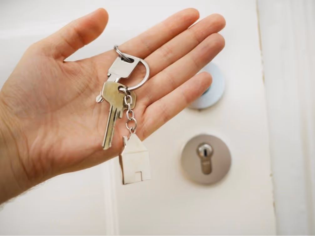 Person holding house keys in front of a door