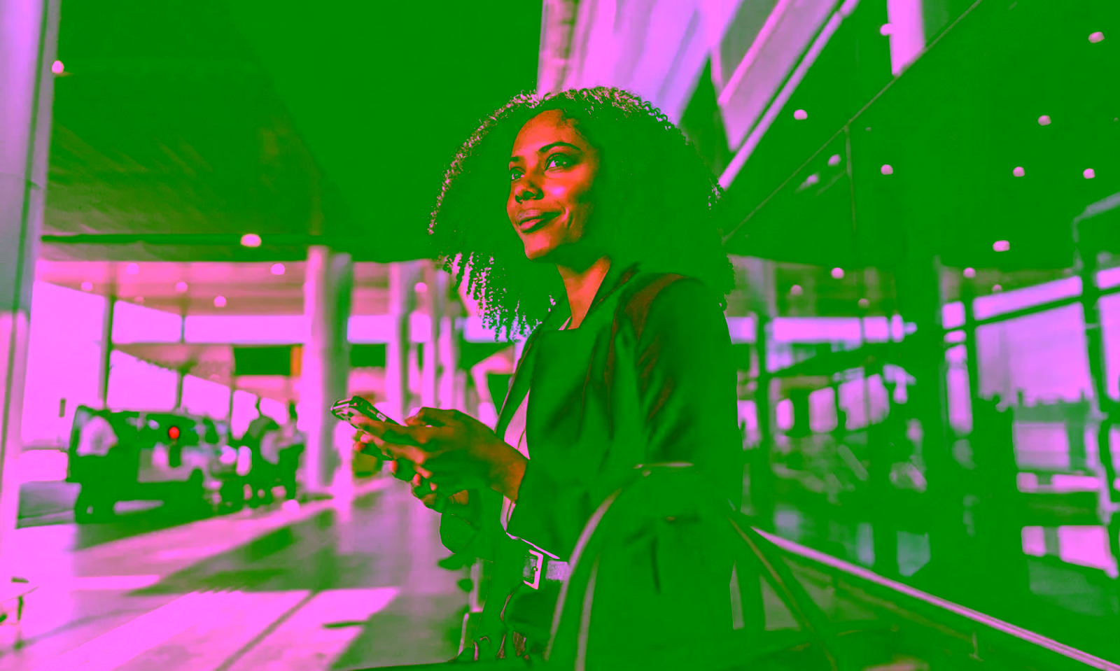woman sitting on a bench holding her phone with her luggage sitting on the bench next to her