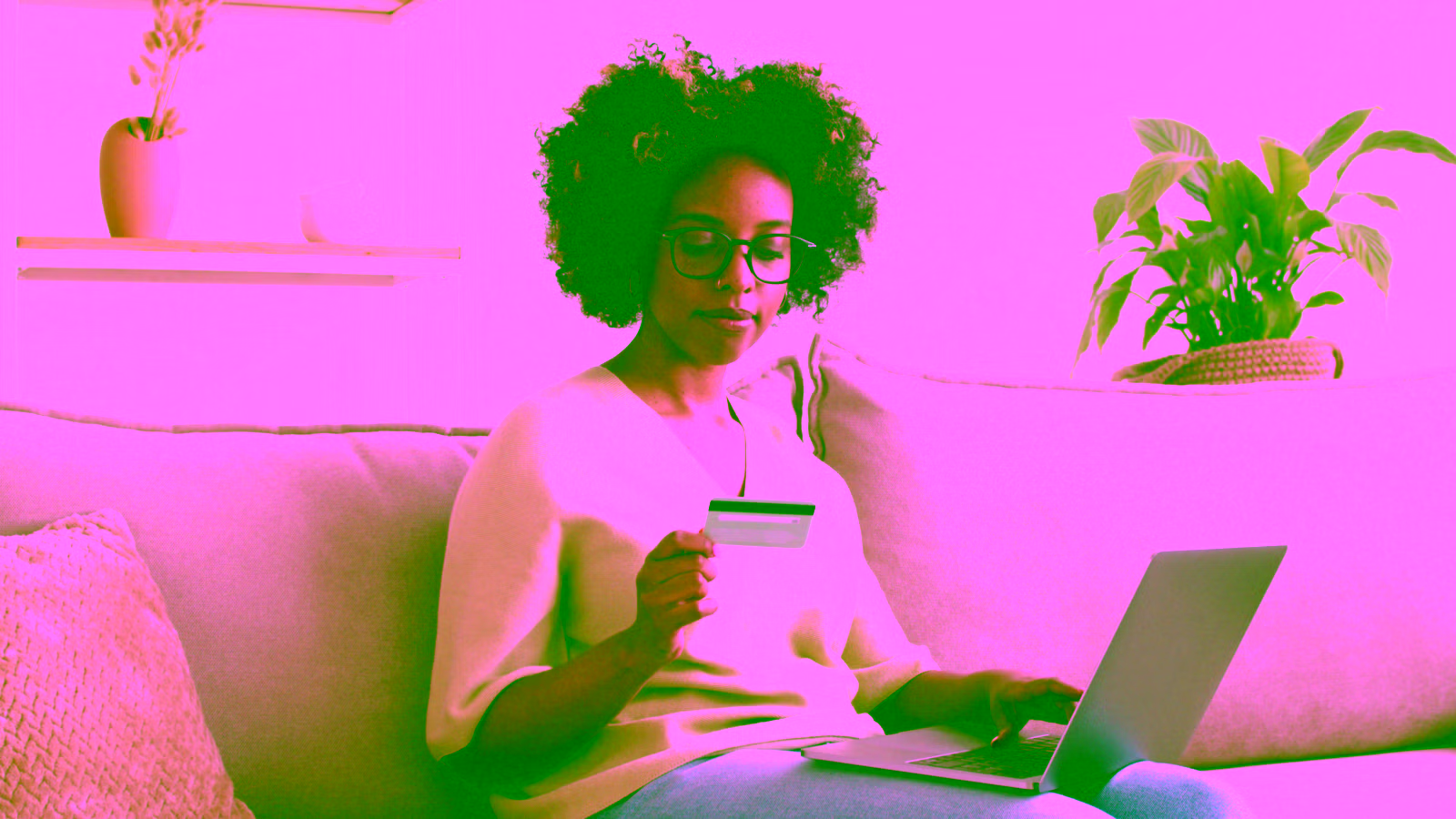 girl sitting on her couch with a laptop and a credit card