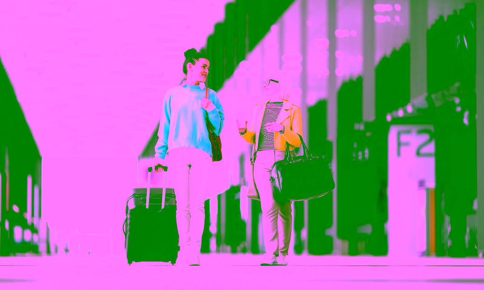 mom and daughter smiling at an airport with their luggage