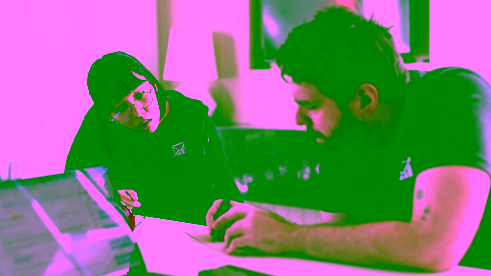 Two coworkers collaborating at a desk with a laptop.