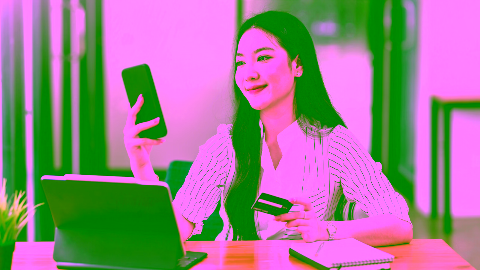 Woman using phone and credit card at desk