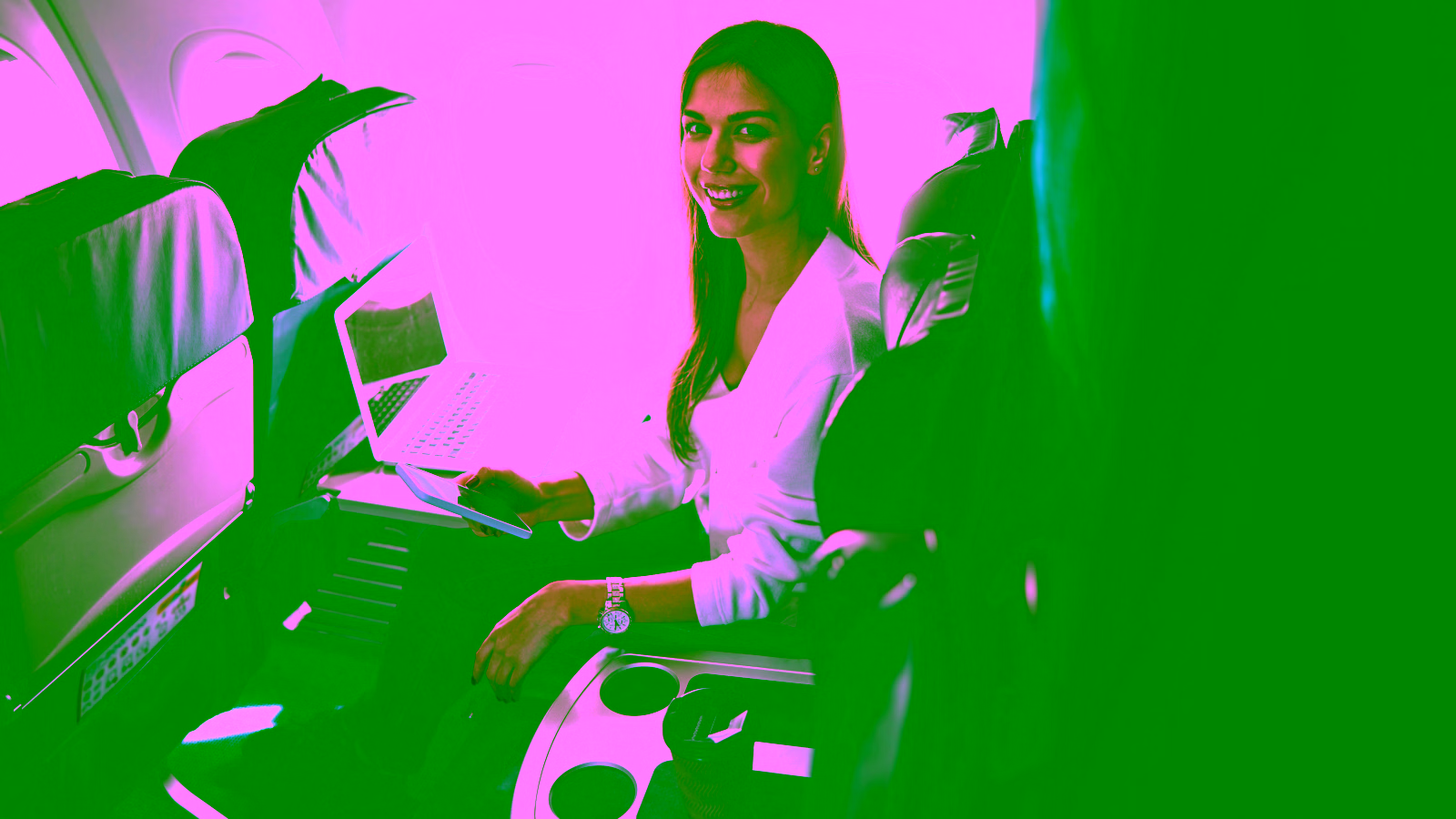 Woman using laptop and phone in airplane