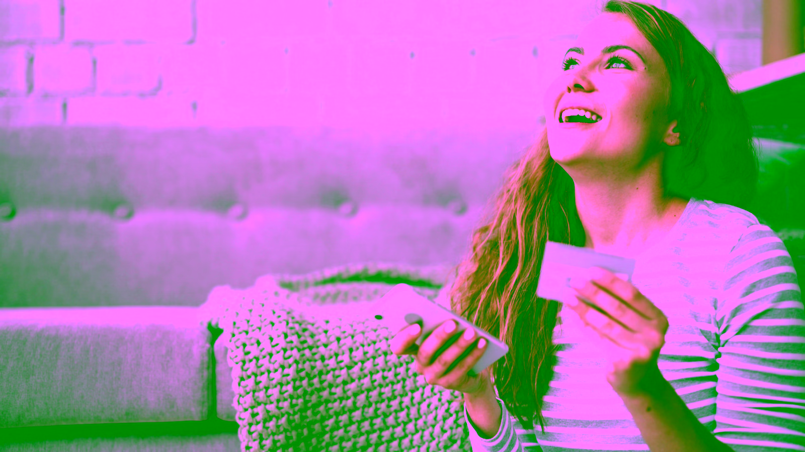 Woman smiling while holding a credit card and phone