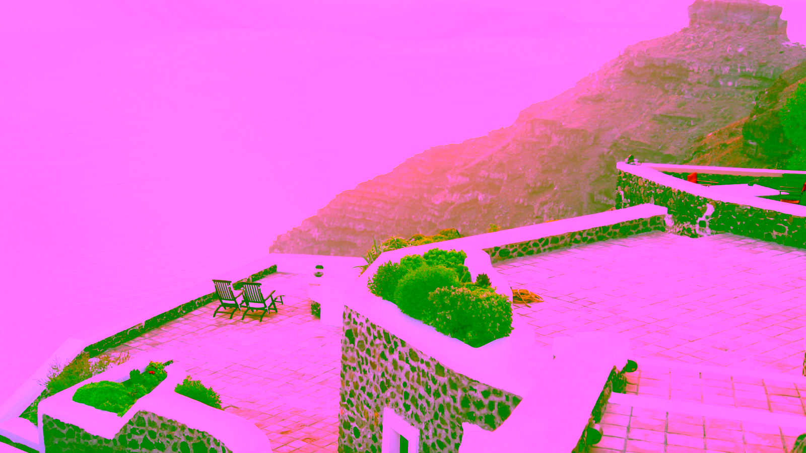 Cliffside terrace with chairs overlooking ocean at sunset