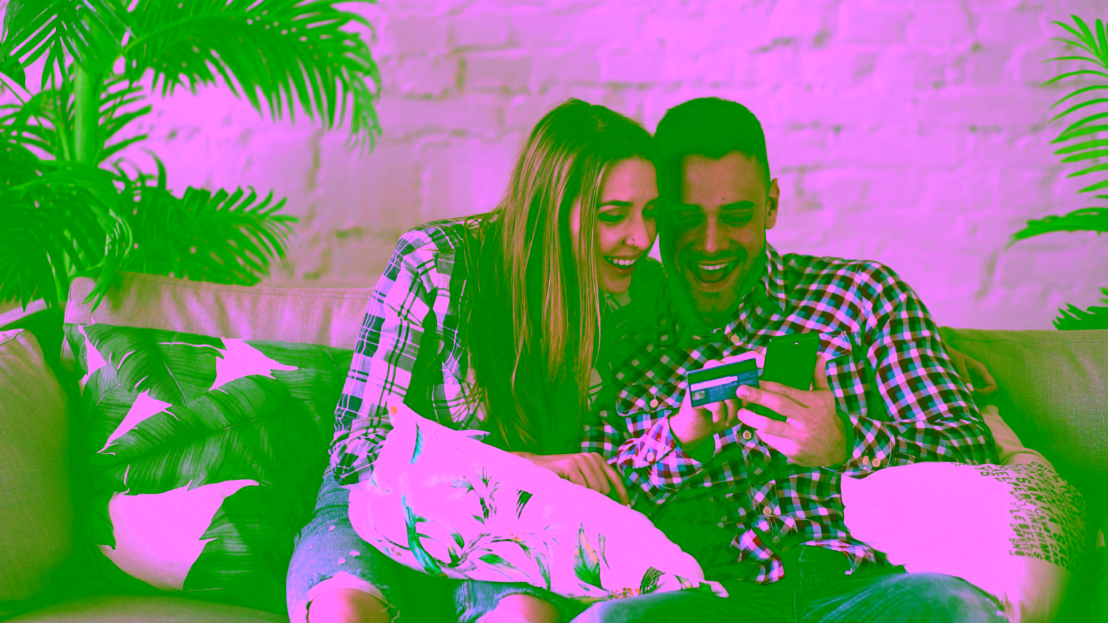 Couple checking a credit card on a smartphone at home