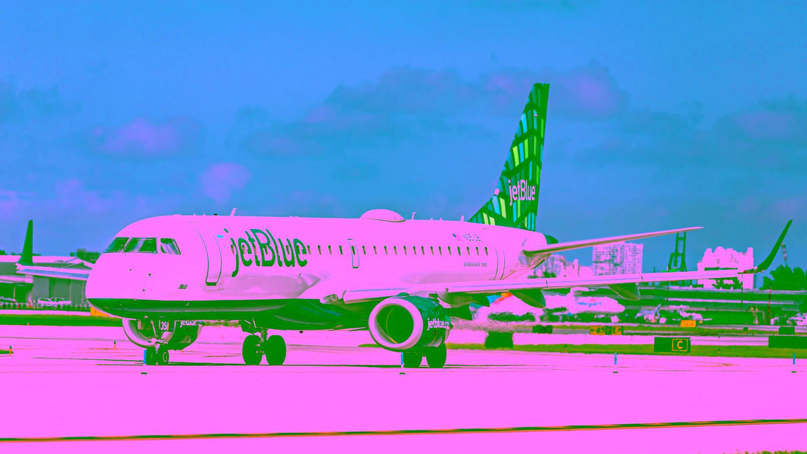 JetBlue aircraft taxiing on airport runway.