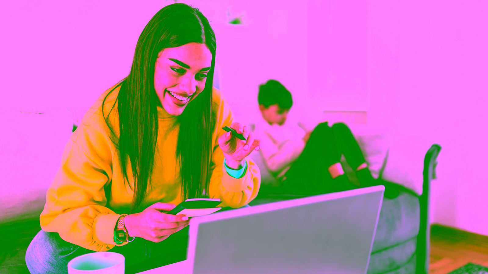 Woman in yellow sweater holding credit card at laptop