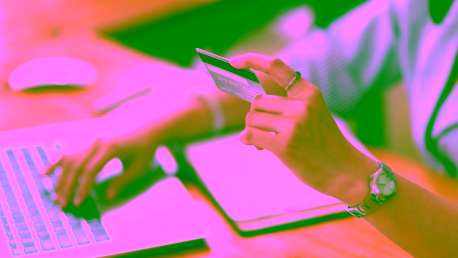 Person holding credit card while using laptop