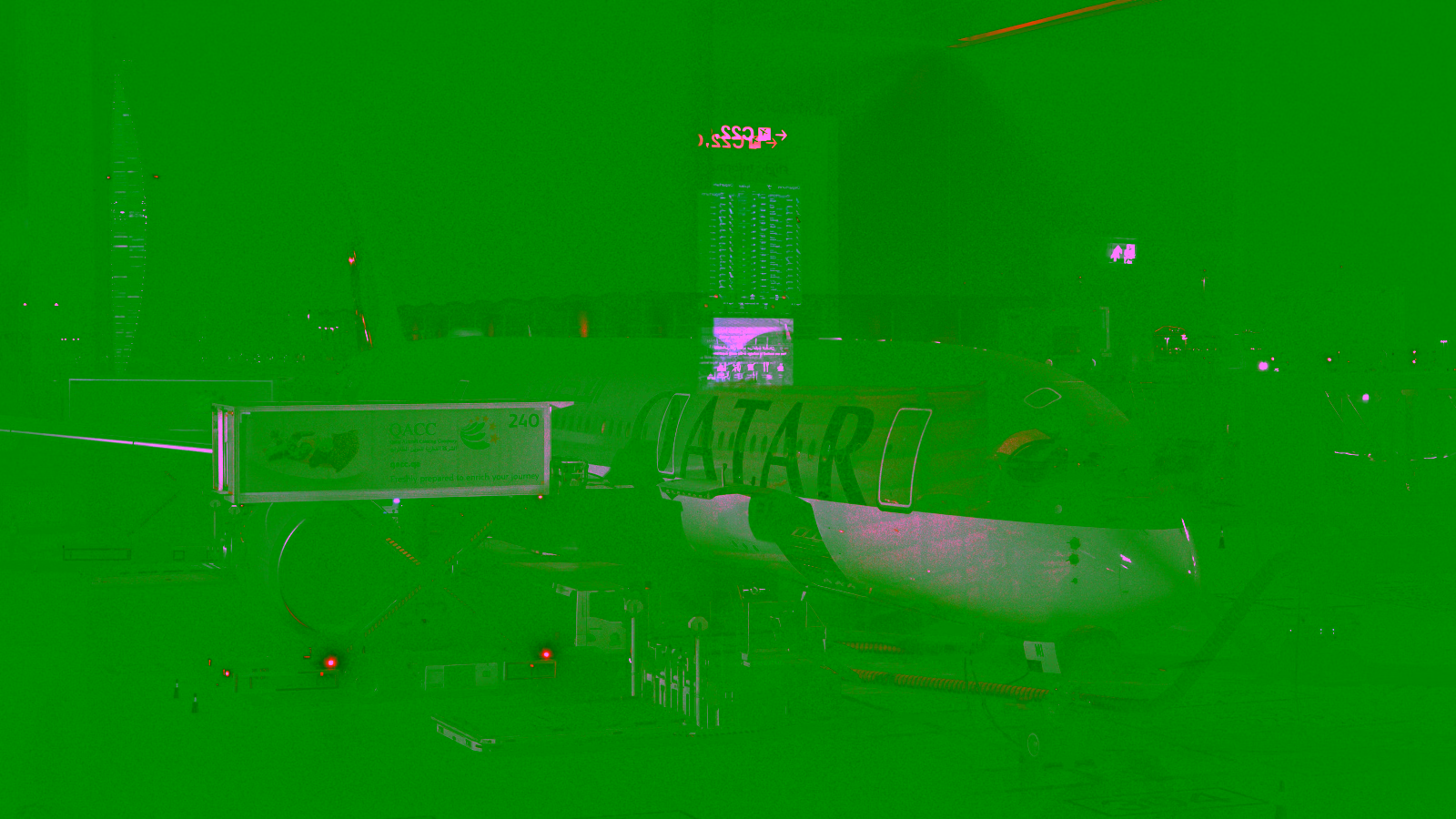 Qatar Airways aircraft parked at gate at night during servicing.