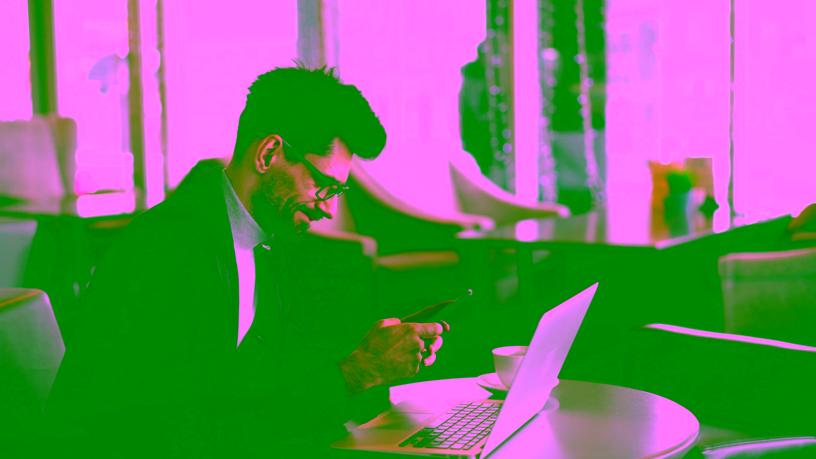 Man on phone with laptop at cafe